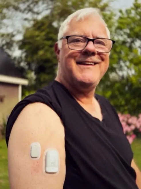Norbert Stellaard smiling and showcasing the Medtrum Nano 300U patch pump and CGM sensor on his arm.